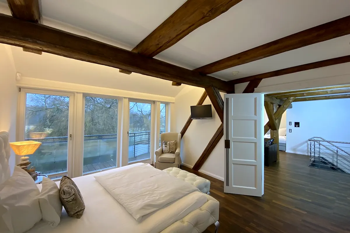 Schlafzimmer der Suite Kronenkranich mit Fenstertür und Blick ins Grüne